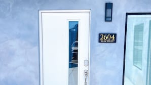 A white door with a glass panel, a keypad lock, and a welcome mat. A sign with "2604 Main Street" is visible on the wall. - Hot Tub/1mi to Downtown/3mi to Coronado/KING Bed/Wifi 300mb+/BBQgrill/Harborside (San Diego)