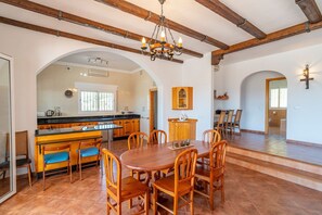 A spacious kitchen with a central island, wooden chairs, and a chandelier.