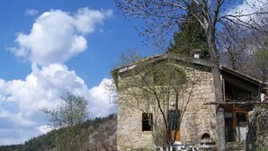 Ein Steinhaus mit einer kleinen Veranda und Sitzgelegenheiten im Freien.