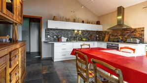 Eine Küche mit einem roten Tisch, weißen Schränken und einer Backsteinwand.
