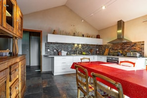 A kitchen with a red table, white cabinets, and a brick backsplash.