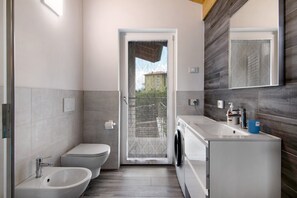 Une salle de bain moderne équipée de toilettes, d’un bidet, d’un lavabo et d’un lave-linge.