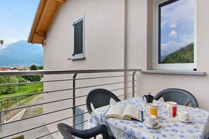Un balcon avec une table dressée pour deux personnes, un livre et une cafetière.