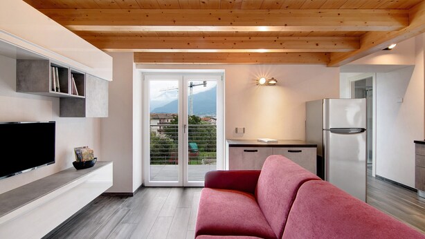 Una cocina moderna con refrigerador empotrado, televisor de pantalla plana en la pared y puerta corrediza de vidrio que da a un área exterior.