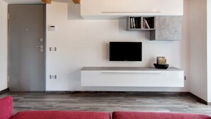 Una sala de estar moderna con un televisor de pantalla plana, estanterías empotradas y una puerta.
