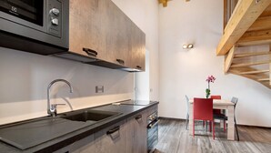 Una cocina moderna con microondas integrado, pileta de acero inoxidable y alacenas de madera.