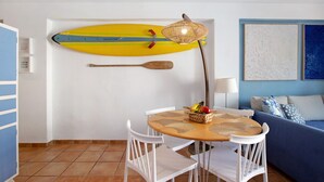 A room with a surfboard, a paddle, a table with a basket of fruit, and a blue sofa. - Holiday Apartment "Blue Fish" with Shared Pool, Private Terrace & Wi-Fi (Benalmádena)
