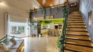 Amplia sala de estar con escalera de madera, comedor y vista a una piscina.