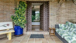 Una entrada de ladrillo con planta en maceta, un banco y un sofá.