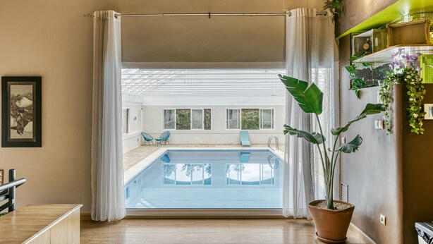 Un interior moderno con piscina, plantas en macetas y vistas al exterior.