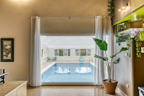Um interior moderno com piscina, plantas em vasos e vista para o exterior.