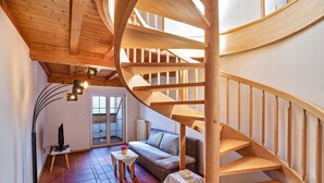 Una escalera de caracol en una habitación con un sofá, una mesita y una lámpara de pie.
