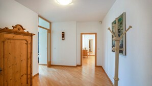 Un couloir doté d’un plancher en bois, d’une armoire en bois et d’un porte-manteau sur lequel est accroché un manteau.