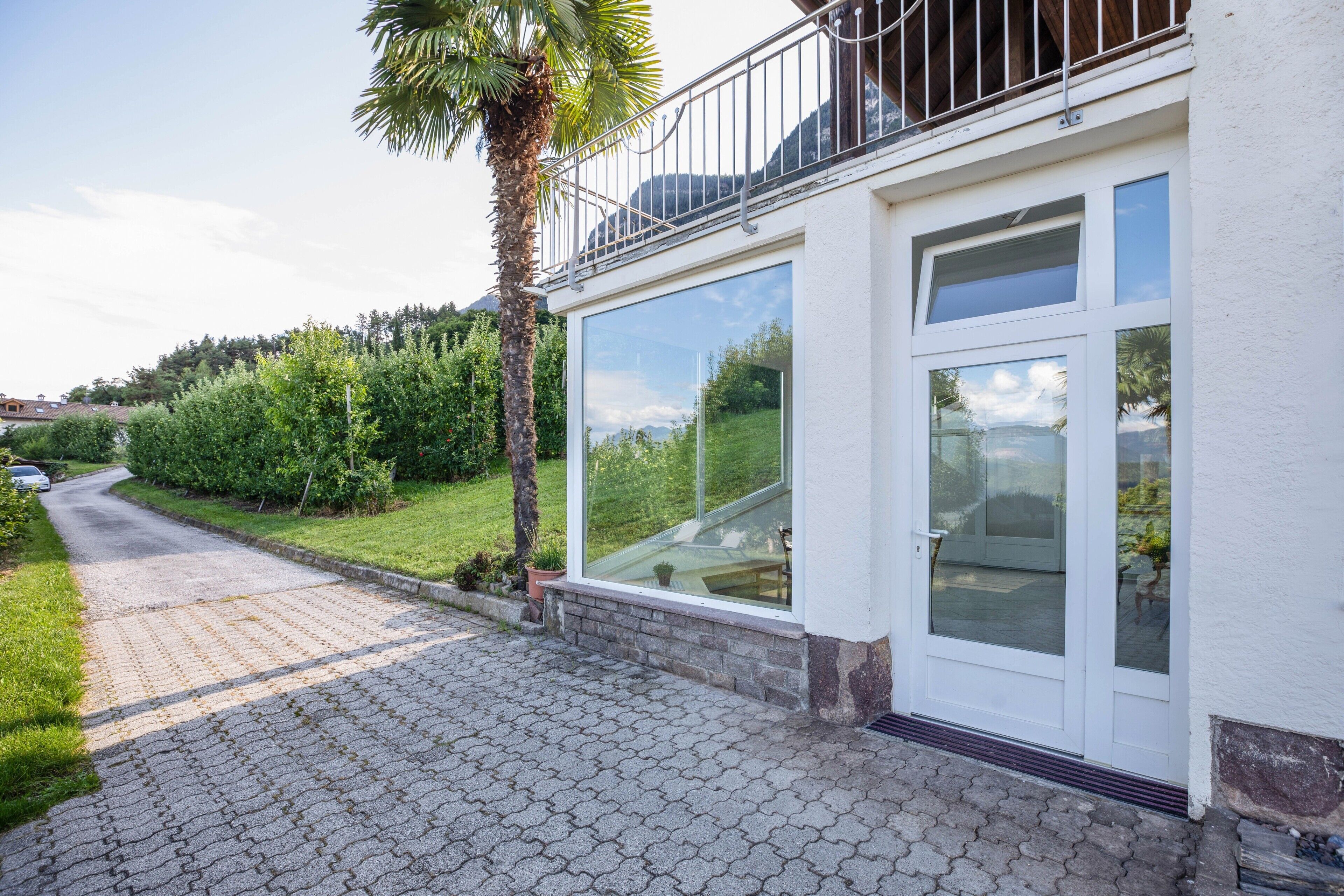 Una casa con entrada pavimentada, balcón y un amplio ventanal.