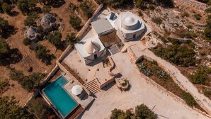 An aerial view of a property with a swimming pool, stone structures, and surrounding vegetation. - Villa 'Trulli Meridiem Con Piscina' with Private Pool, Wi-Fi and Air Conditioning (Ostuni)