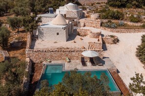 Un complejo turístico con edificios de piedra, piscina y mesas al aire libre.