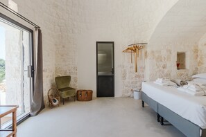 Een slaapkamer met een bed, een stoel, een mand en een deur.