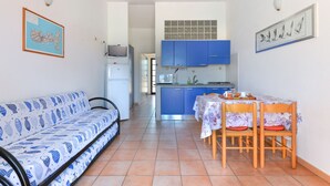 Un espacio habitable compacto con sofá, una mesa de comedor con sillas, una zona de cocina y un televisor.
