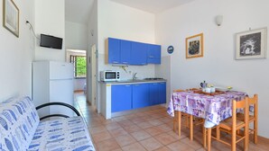 A compact kitchen with blue cabinets, a microwave, and a dining table with chairs.