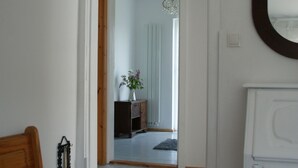 Un dormitorio con cama, cómoda, espejo y un pasillo que lleva a otra habitación.