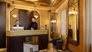 A reception desk with a modern design, a large mirror, and elegant lighting fixtures. - Maison Cassandre (Paris)