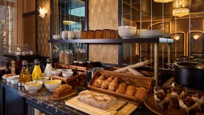 A breakfast buffet with various food items, including bread, pastries, and condiments. - Maison Cassandre (Paris)