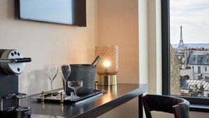 A hotel room with a view of the Eiffel Tower, a coffee machine, a glass of water, and a decorative lamp. - Maison Cassandre (Paris)