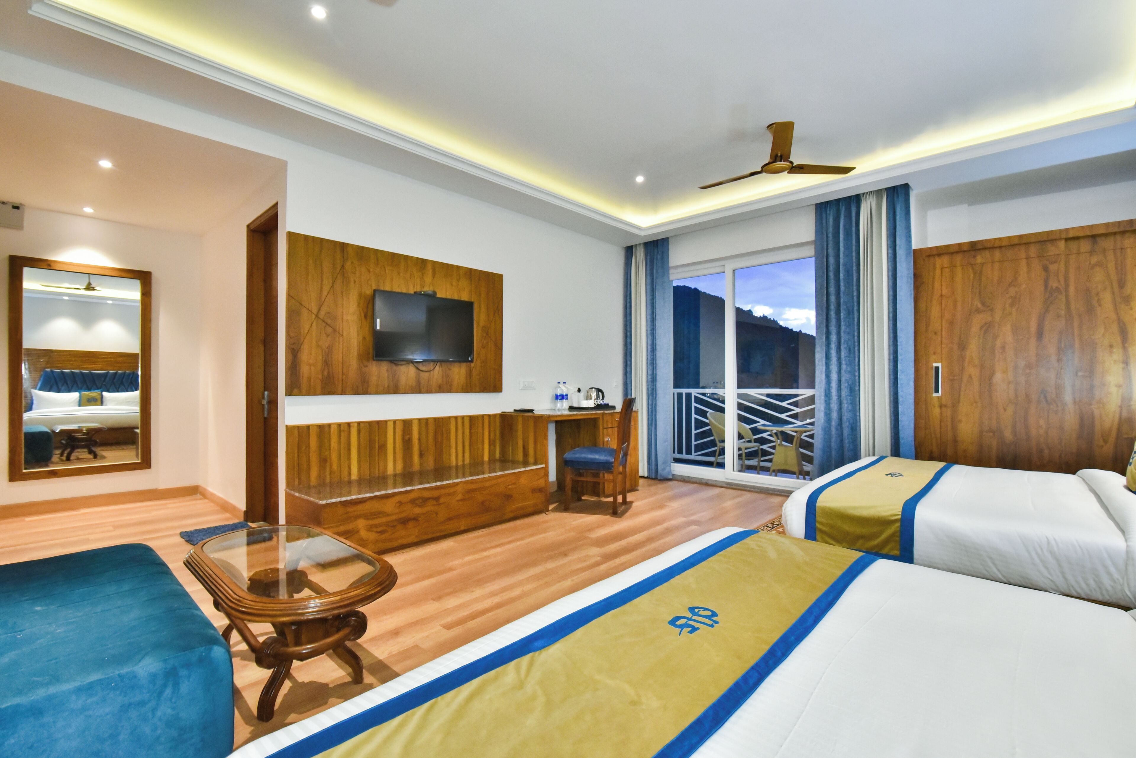 Une chambre d’hôtel avec un lit, un bureau, une chaise, une télévision et un balcon avec vue.