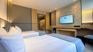 A hotel room with two beds, a TV, and a mirror.
