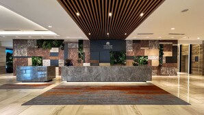 Eine moderne Hotelhalle mit einer Rezeption, einem Concierge-Bereich und einem Schild für Hotel Royal Signature.