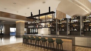 Eine moderne Bar mit einer langen Theke und mehreren Hockern, umgeben von Flaschenregalen.