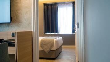 A hotel room with a bed, a desk, and a TV on the wall.
