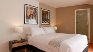 A bedroom with a bed, nightstands, and two framed pictures on the wall.