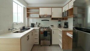 A compact kitchen with white cabinets, a stainless steel stove, and a microwave.