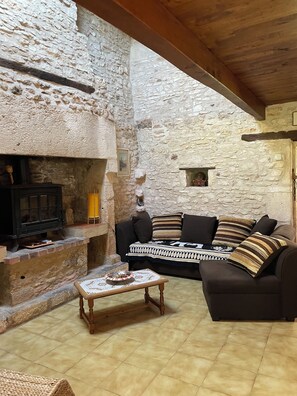 Une pièce aux murs de pierre, avec une cheminée, un canapé et une petite table.