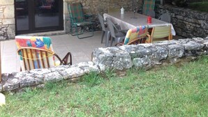 Eine Terrasse im Freien mit einer Steinmauer, Holzbalken und einem Tisch mit Stühlen.