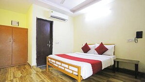 A room with a wooden bed, a wardrobe, a door, and an air conditioning unit. - Hotel Raaso inn Nawada Metro By Arrow  (New Delhi)