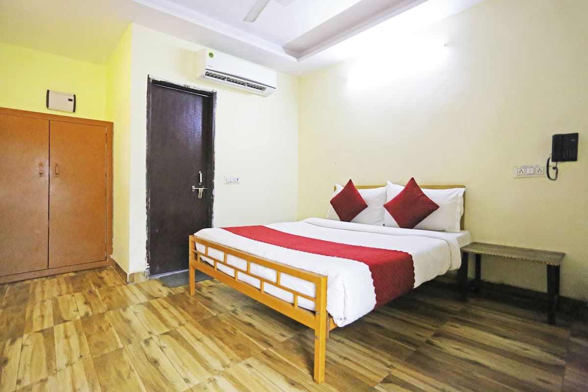 Una habitación con una cama de madera, un armario, una puerta y un equipo de aire acondicionado.
