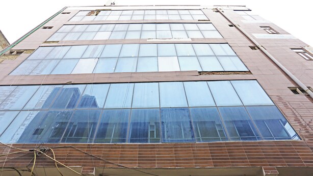 A multi-story building with large windows and a sign for 'ALSTONE'. - Hotel Raaso inn Nawada Metro By Arrow  (New Delhi)