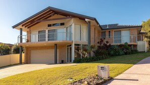 Ein zweistöckiges Haus mit Garage, Balkon und gepflegtem Rasen.