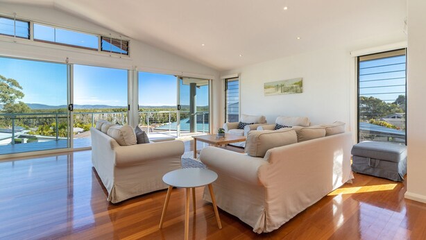 Ein geräumiges Wohnzimmer mit großen Fenstern, einem Balkon und Blick auf die Landschaft.