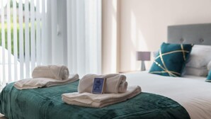 A neatly made bed with a green bedspread and two folded towels on it. - Modern 1B Central Manchester + Free Parking (Salford)
