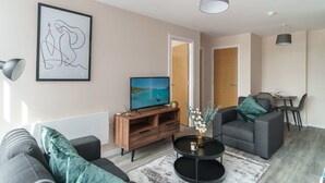 A modern living room with a TV, sofa, and coffee table. - Modern 1B Central Manchester + Free Parking (Salford)