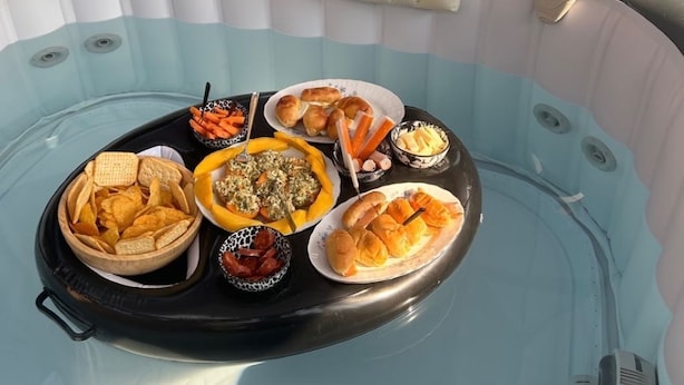 A hot tub with a tray of snacks and drinks, surrounded by a sofa with cushions and a small table with a glass of water. - La Teranga du Saulchoix (Clairy-Saulchoix)