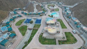 A mountainous resort with multiple buildings, winding roads, and a central courtyard with a pool.