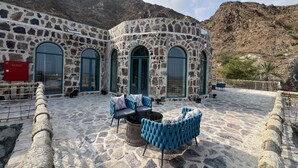 A stone building with arched windows and a stone patio with outdoor seating.