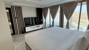 A modern hotel room with a large bed, a TV, and a view of a mountainous landscape.