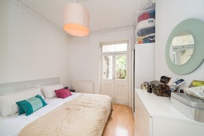 Relax in a serene bedroom with a large bed, white dresser, and stylish window.