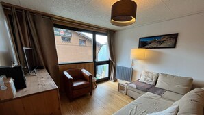 Habitación de hotel con un escritorio de madera, un sillón de cuero, un sofá, una lámpara y un cuadro en la pared.