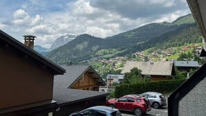 Un pueblo de montaña con casas de madera tradicionales, cielo despejado y vistas de las colinas circundantes.